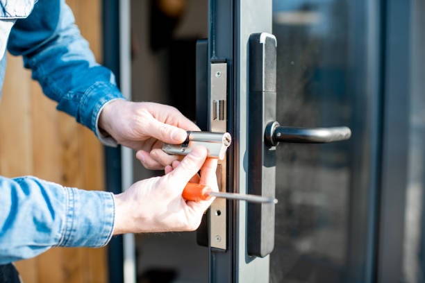 Technician repairing a door lock with a screwdriver, illustrating residential locksmith services for improved home security.