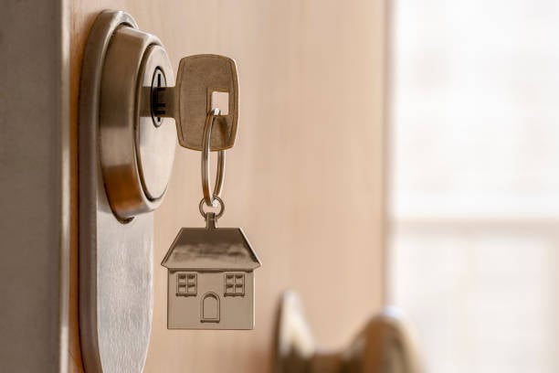 Key in a door lock with a house-shaped keychain, symbolizing residential security and locksmith services.