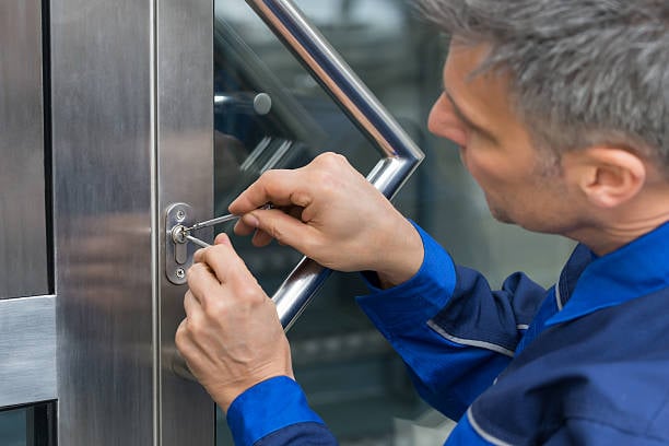 Locksmith working on a commercial door lock, using a screwdriver to repair or install security hardware.